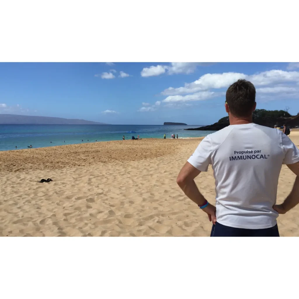Magnigique photo de dos de Steve Vermette admirant le sublime panorama de la mer à Maui, Hawaï, avec son chandail sur lequel apparaît bien en vue l'écriture : " Propulsé par IMMUNOCAL".