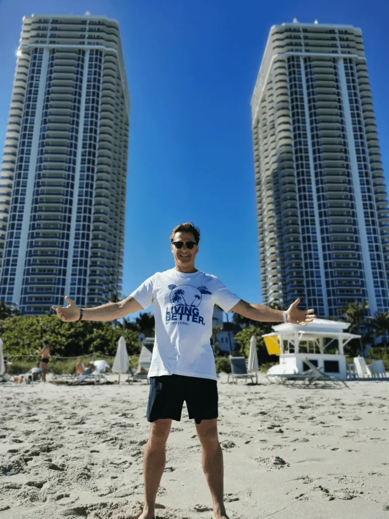 Magnigique photo de Steve Vermette exhultant de bonheur devant les gigantesques tours DIAMONDS de Miami Beach avec les bras ouverts vers le ciel pour mettre en évidence l'énoncé de son chandail " LIVING BETTER", style de vie Immunotec oblige!